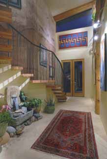 Interior wooden staircase with artistic metal railing that is part of the entry of the Poured Earth home of architect, Michael Frerking